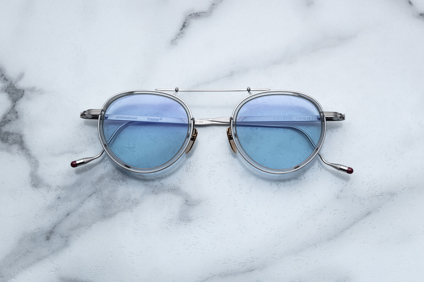 Overhead view of silver rimmed sunglasses with round blue lenses