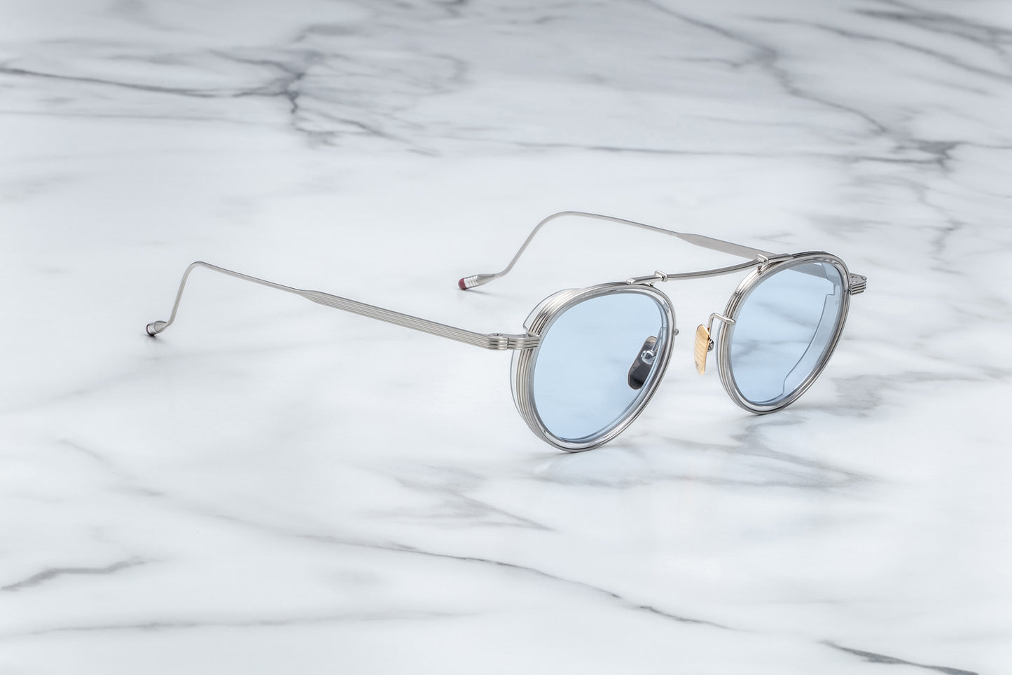 Side view of silver rimmed sunglasses with round blue lenses