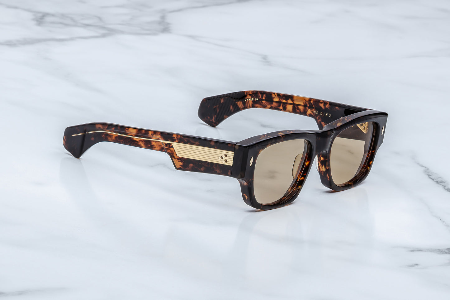 Sunglasses with tortoiseshell frame and gold accents on a marble surface