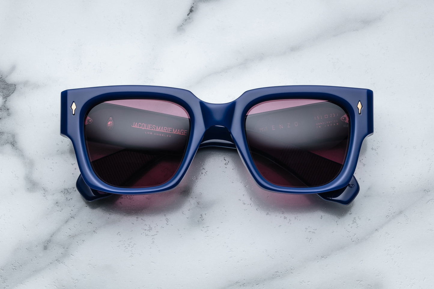 Overhead view of rectangular royal blue sunglasses with red lenses and silver accents