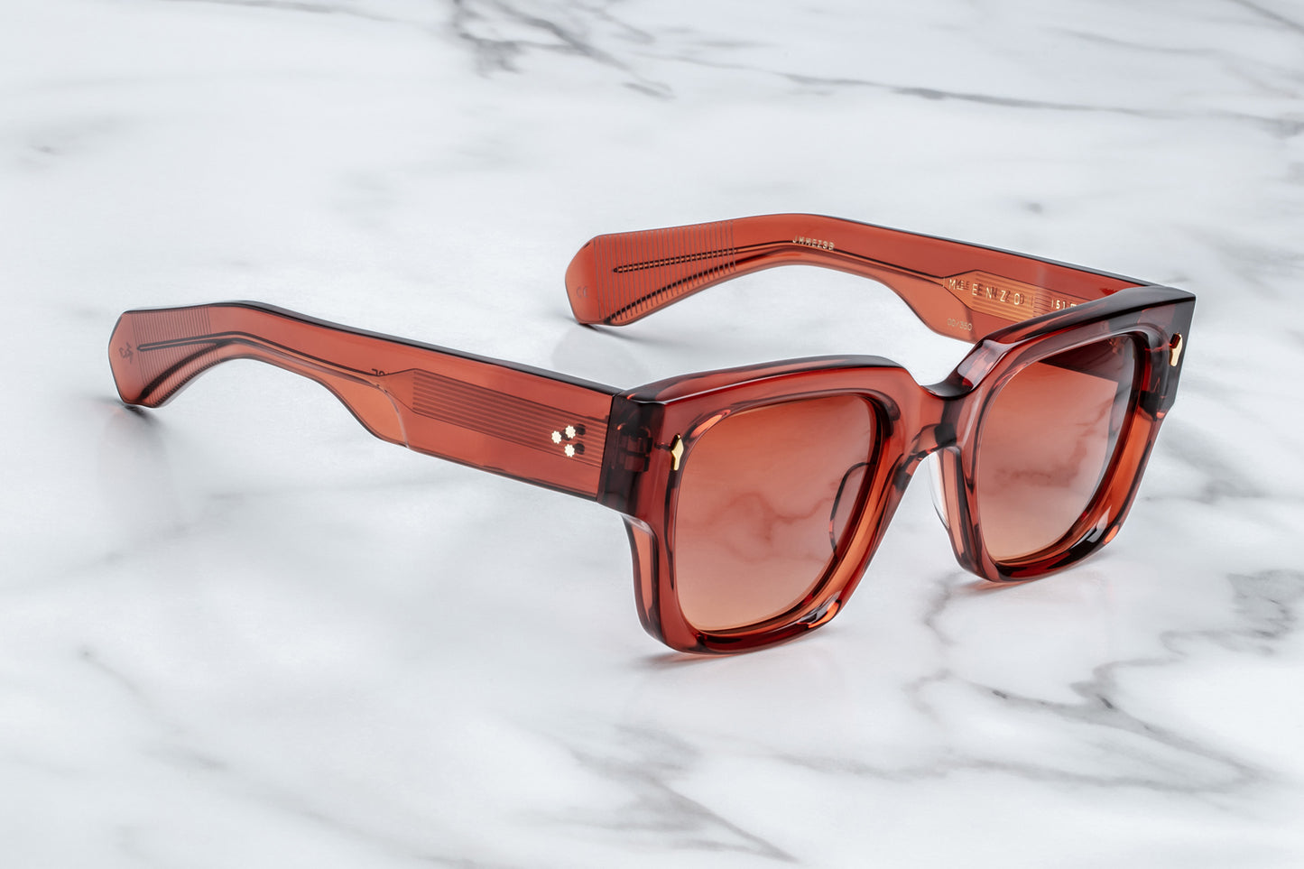 Side view of rectangular translucent red sunglasses with orange lenses and gold accents