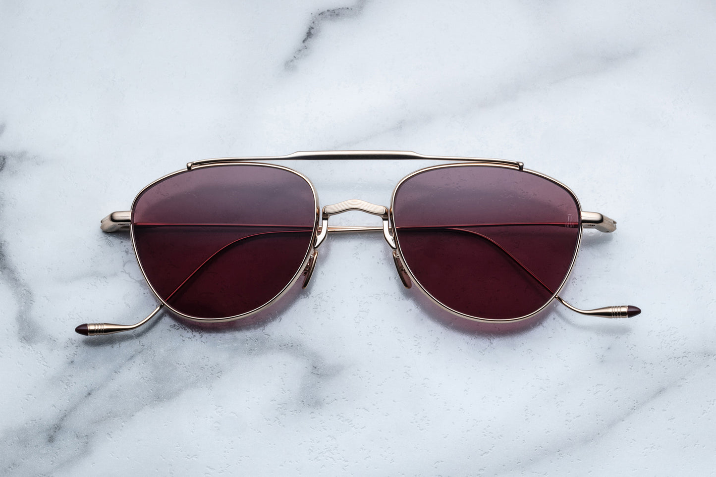 Overhead view of oval shaped sunglasses with mahogany lenses and a light gold frame