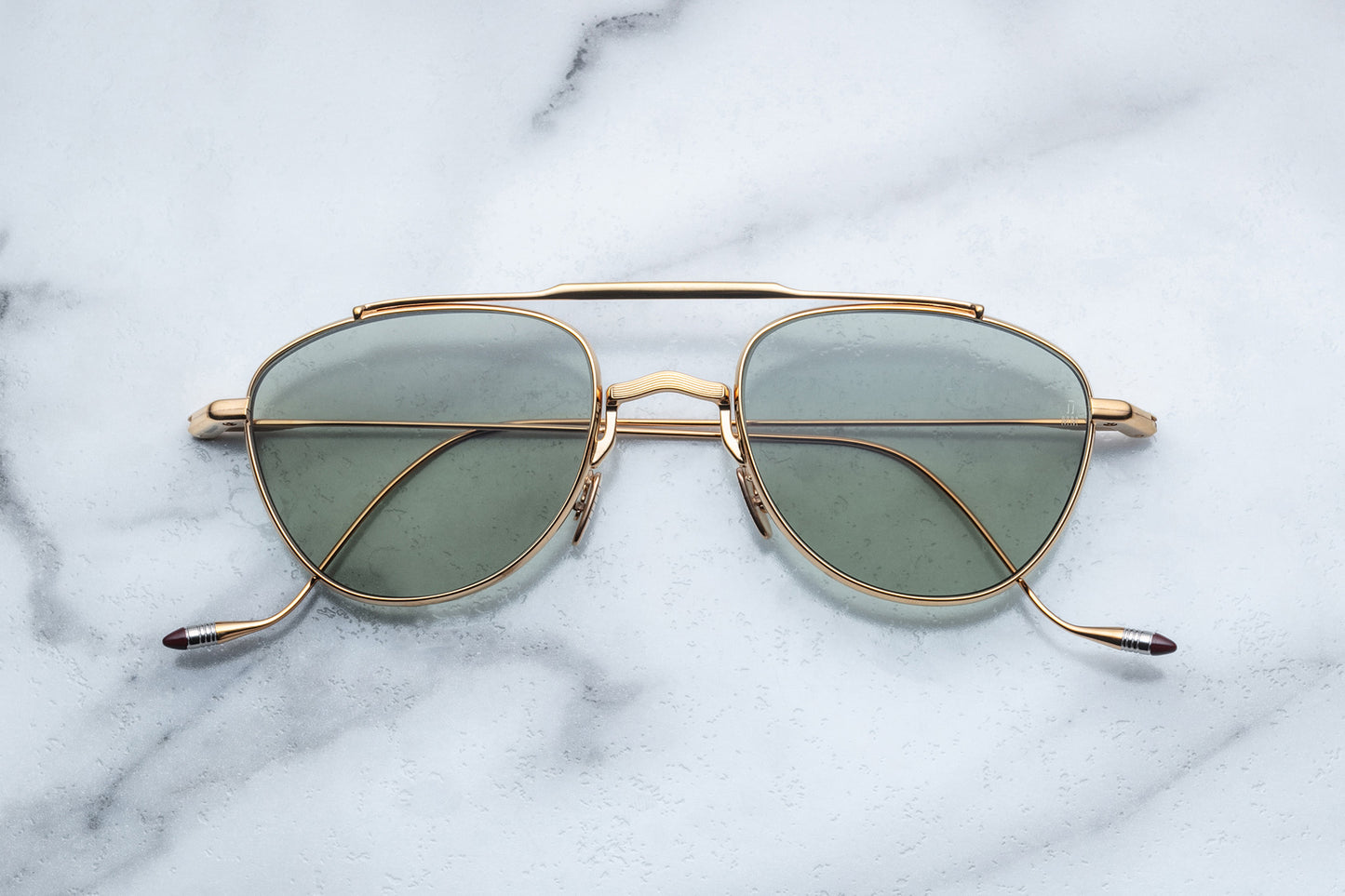 Overhead view of oval shaped sunglasses with bottle green lenses and a gold frame