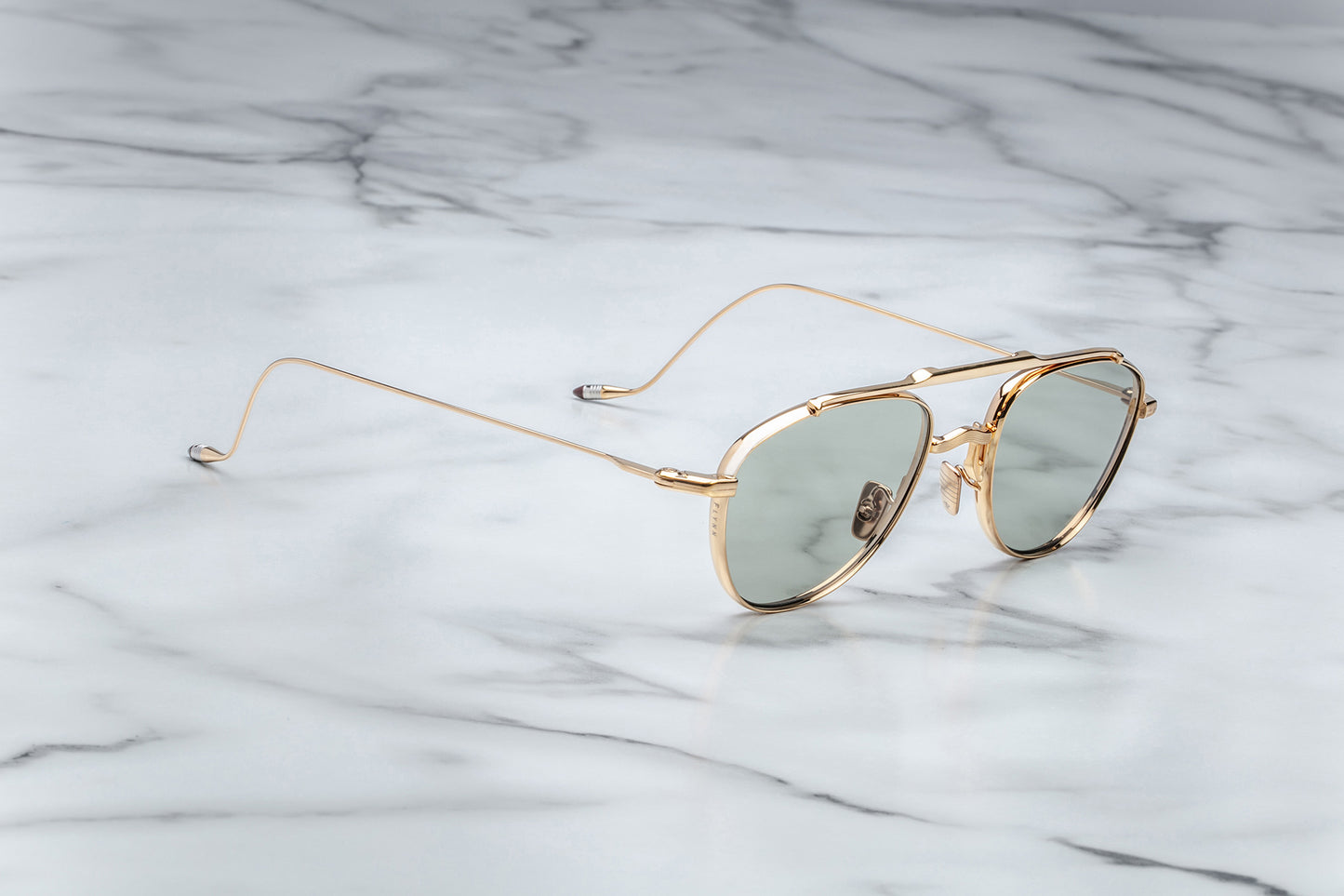 Side view of oval shaped sunglasses with bottle green lenses and a gold frame
