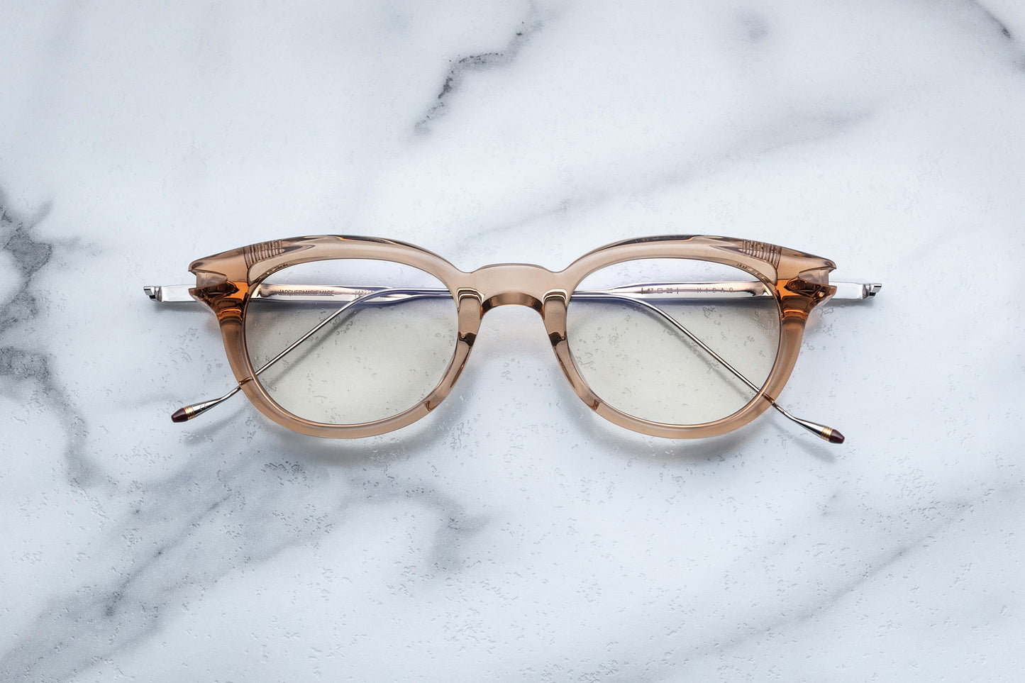 Overhead view of round translucent beige eyeglasses with silver accents