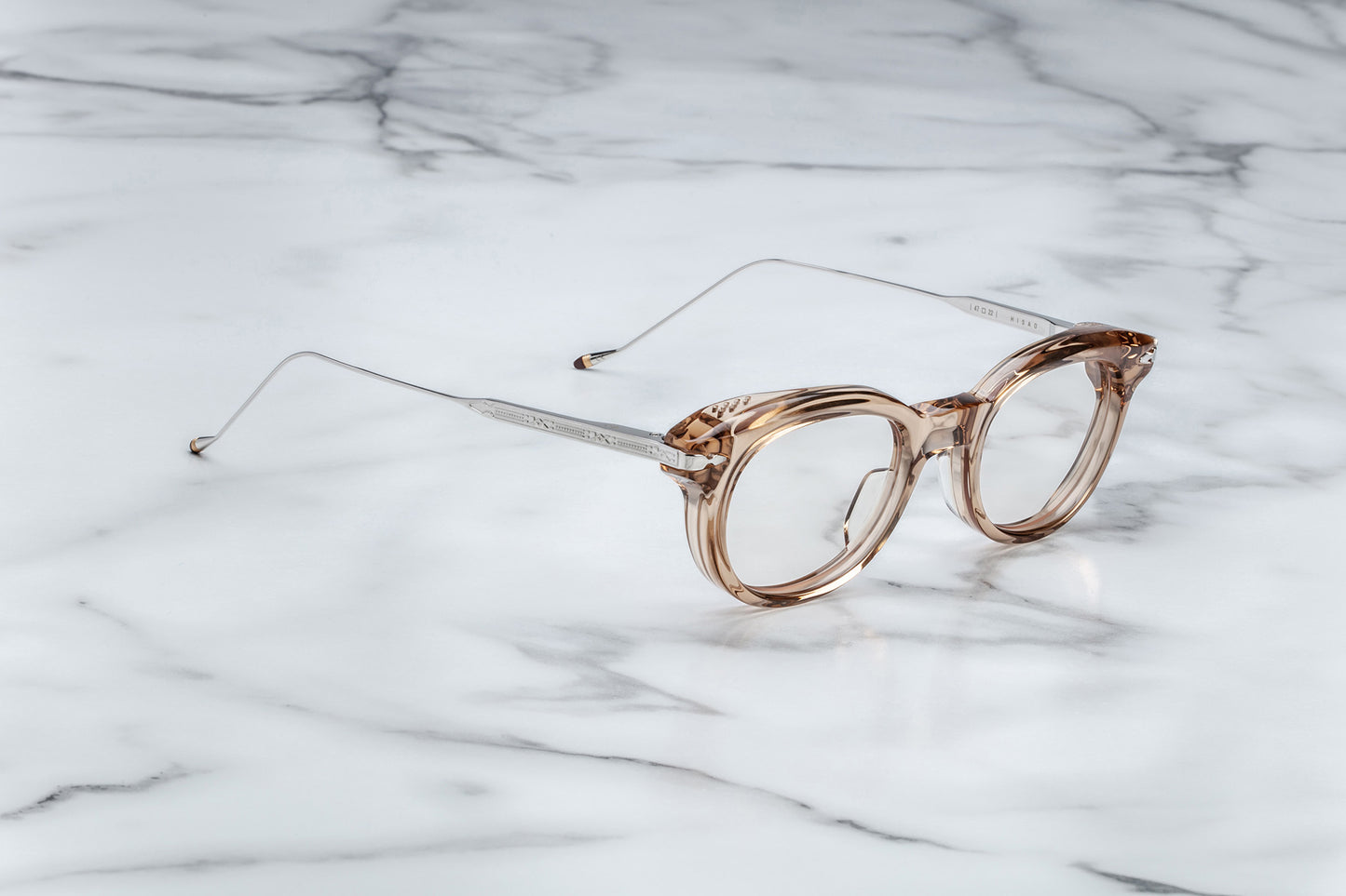 Side view of round translucent beige eyeglasses with silver accents
