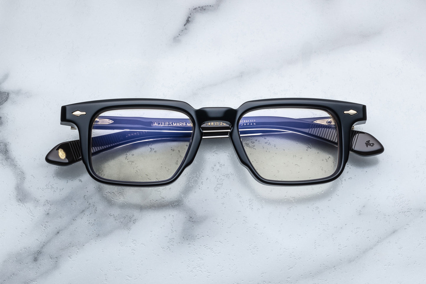 Overhead view of black rectangular eyeglasses with gold accents