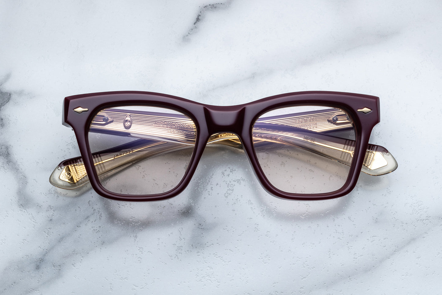 Overhead view of rectangular eyeglasses with burgundy frames and gold accents