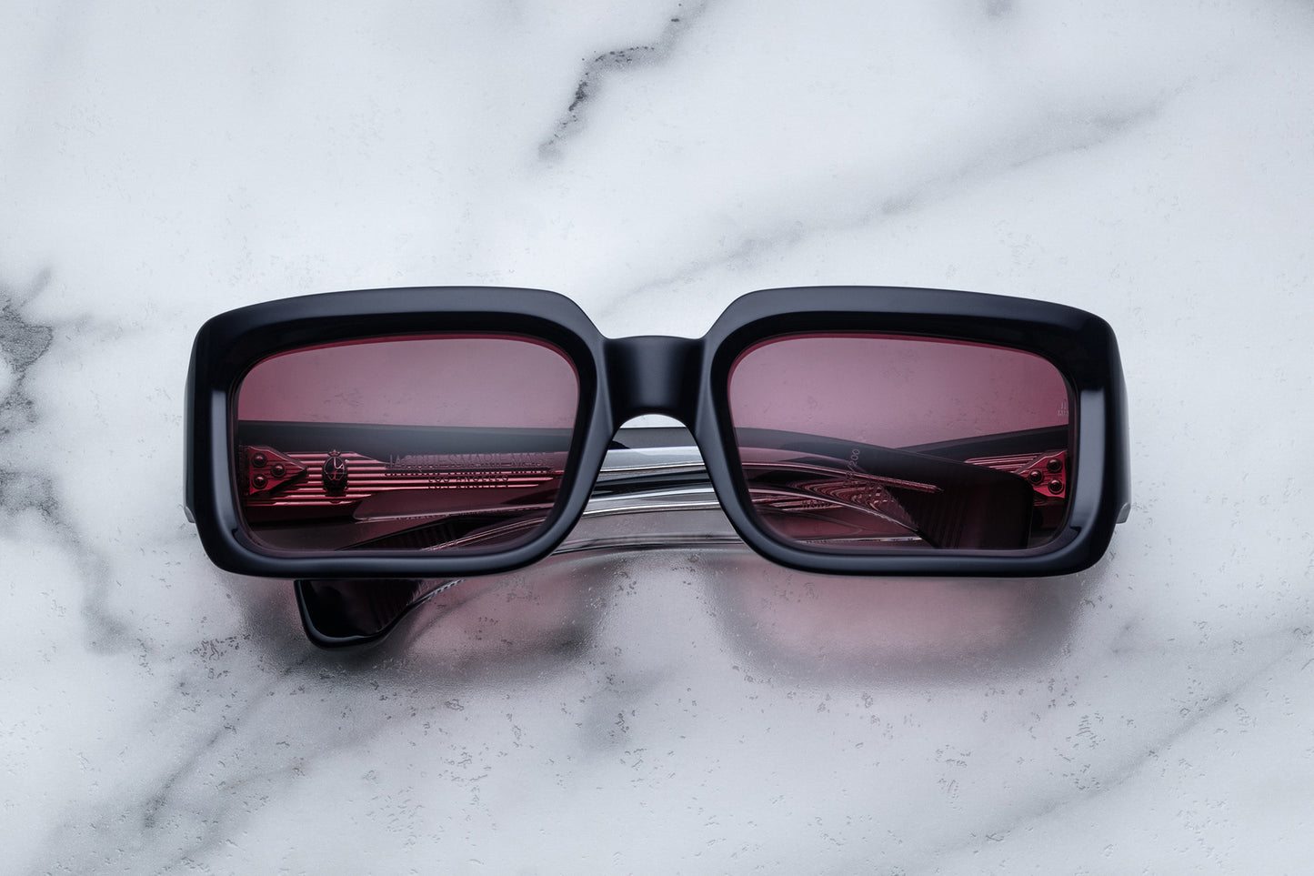 Overhead view of black rectangular sunglasses with burgundy lenses