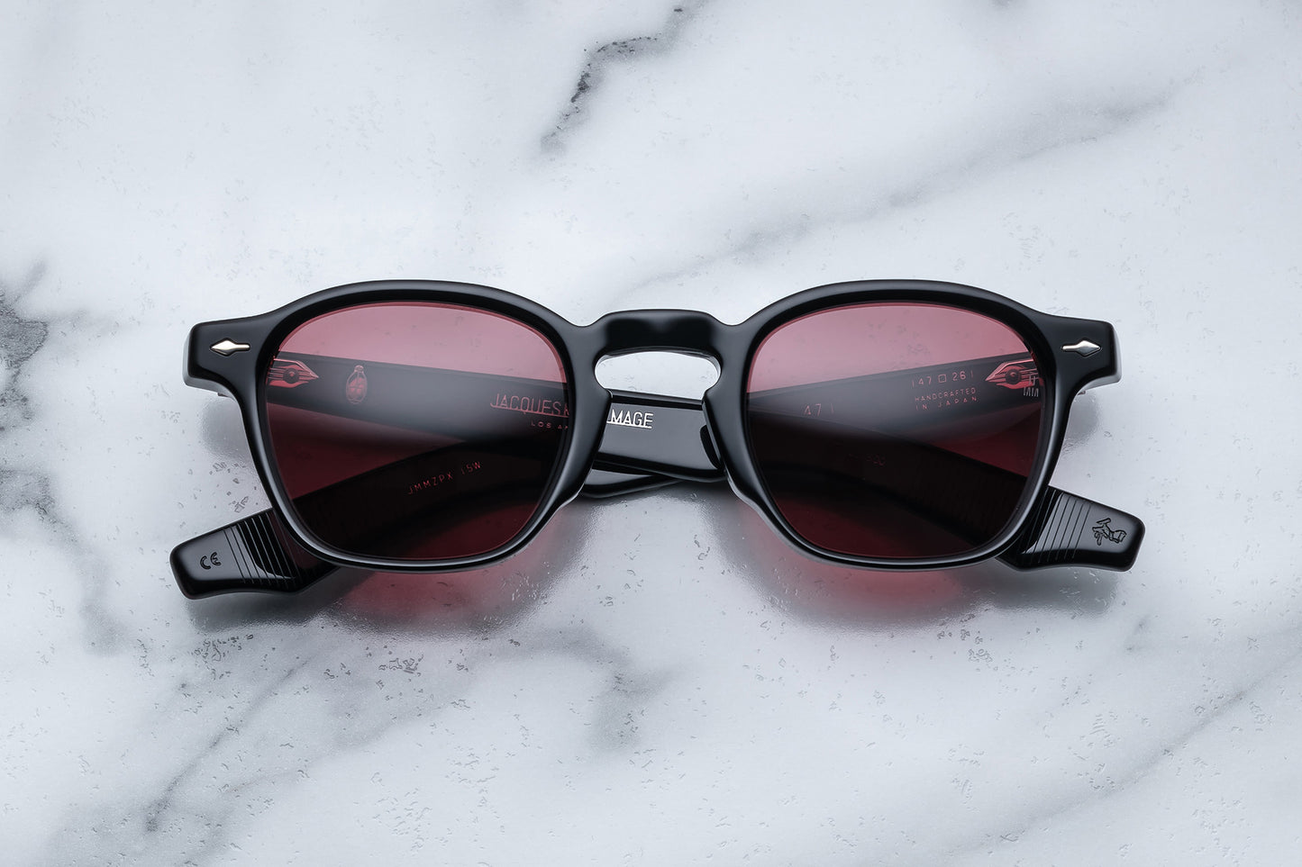 Overhead view of black rounded rectangular sunglasses with red lenses