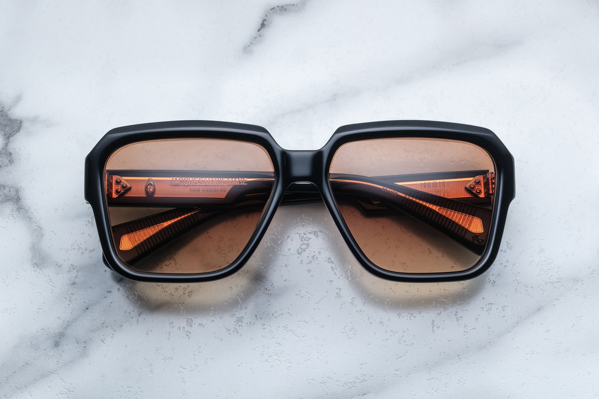 Overhead view of rounded rectangular black sunglasses with brown lenses
