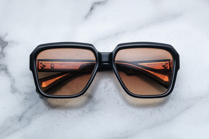 Overhead view of rounded rectangular black sunglasses with brown lenses
