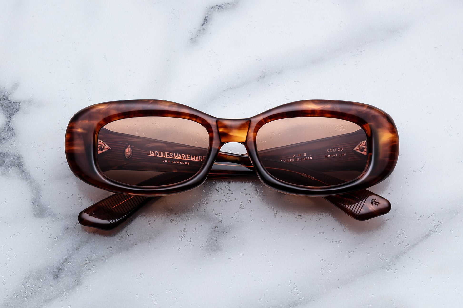 Sunglasses with tortoiseshell frame and brown lenses on a marble surface