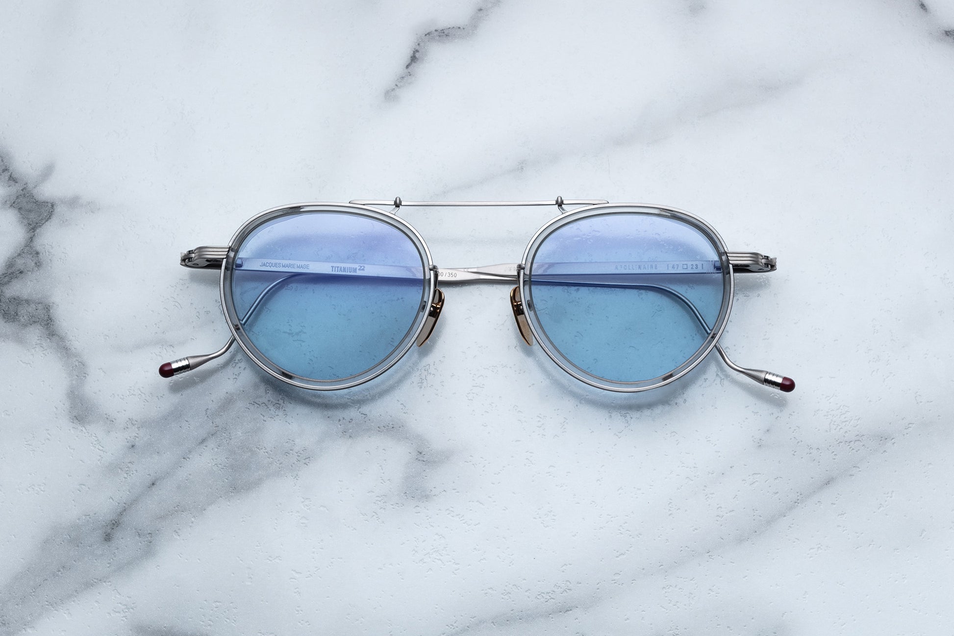 Overhead view of silver rimmed sunglasses with round blue lenses
