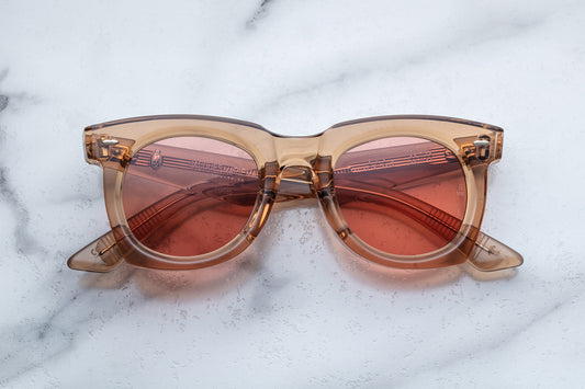 Overhead view of tan translucent sunglasses with pink lenses