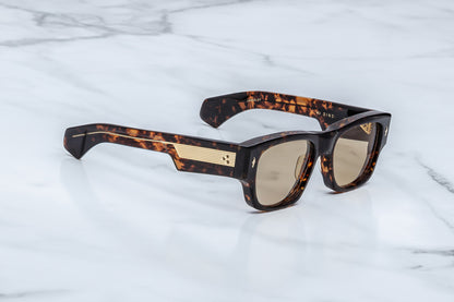 Sunglasses with tortoiseshell frame and gold accents on a marble surface