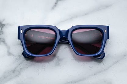 Overhead view of rectangular royal blue sunglasses with red lenses and silver accents