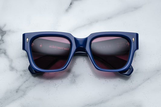 Overhead view of rectangular royal blue sunglasses with red lenses and silver accents
