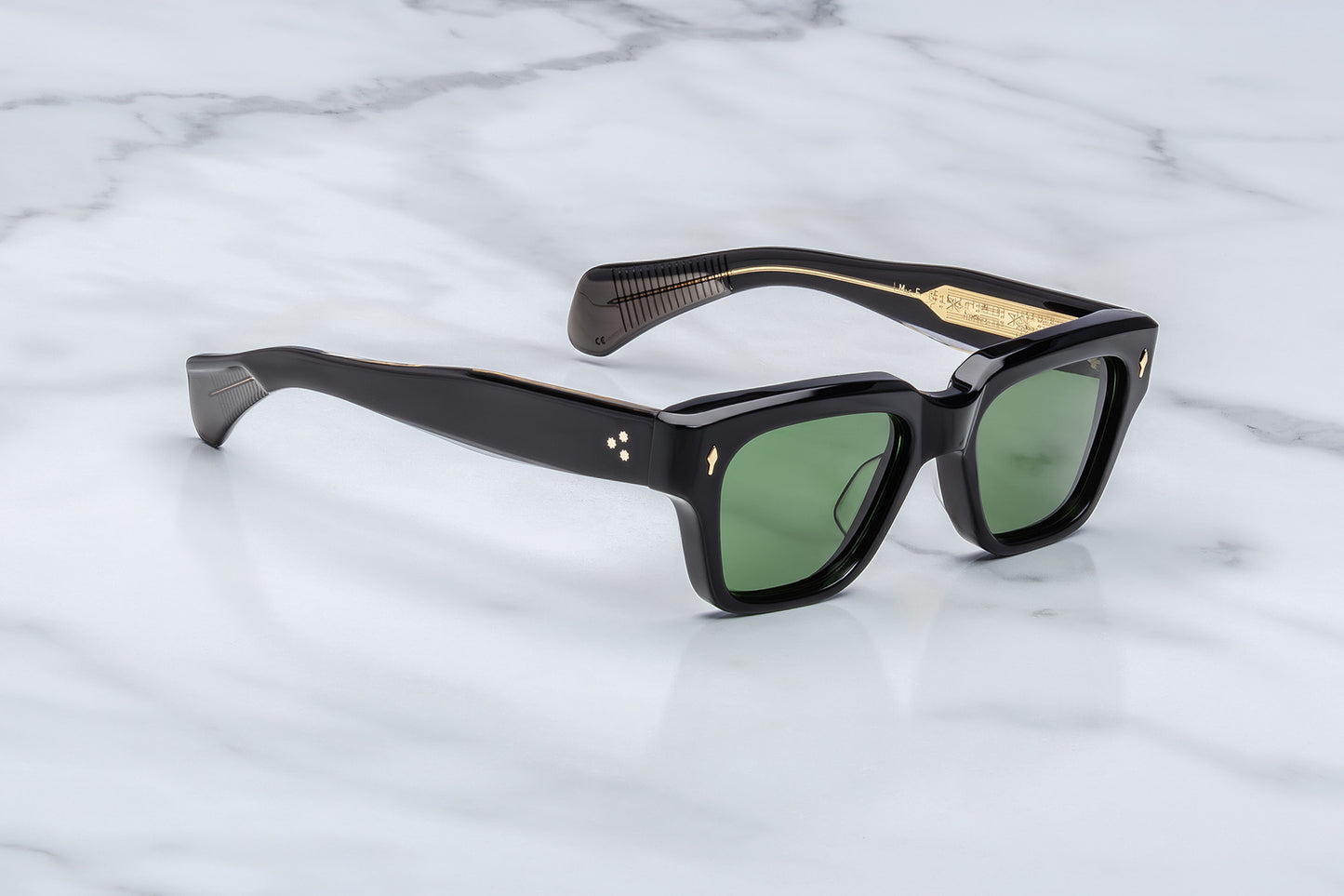 Black sunglasses with green lenses on a marble surface