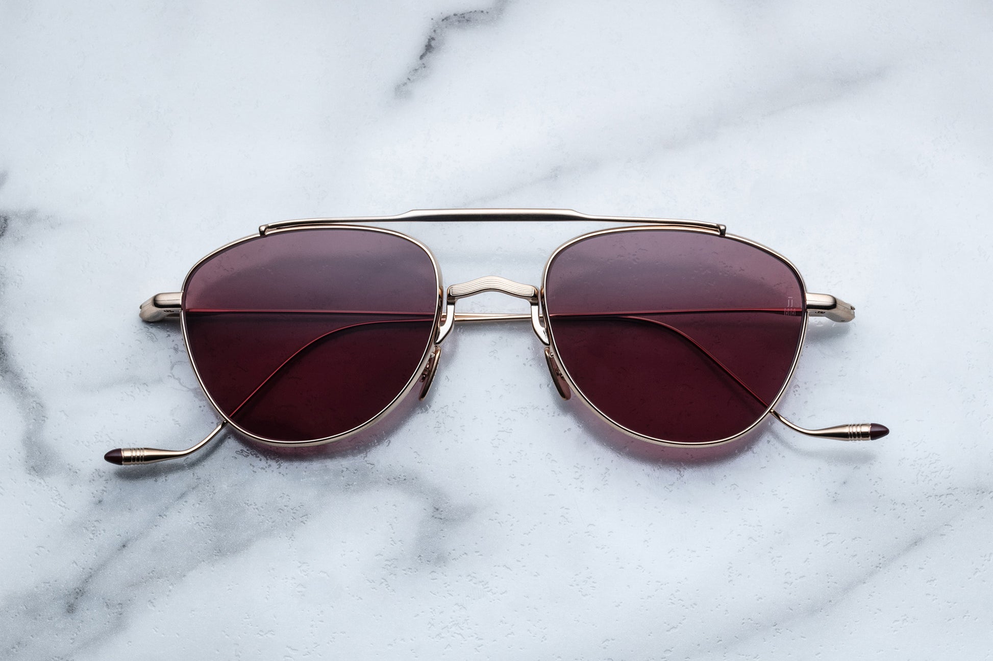 Overhead view of oval shaped sunglasses with mahogany lenses and a light gold frame