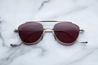 Overhead view of oval shaped sunglasses with mahogany lenses and a light gold frame