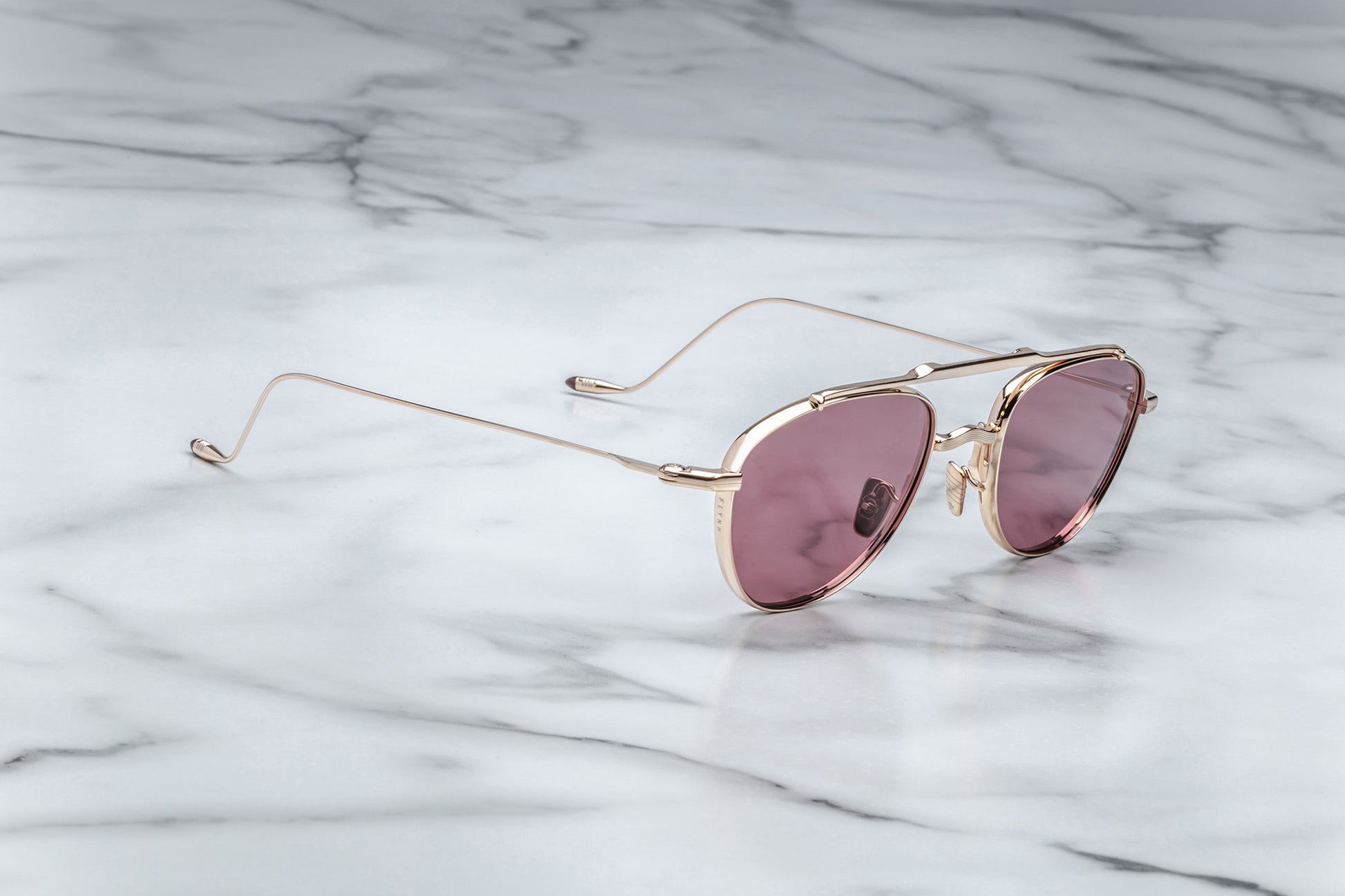 Side view of oval shaped sunglasses with mahogany lenses and a light gold frame
