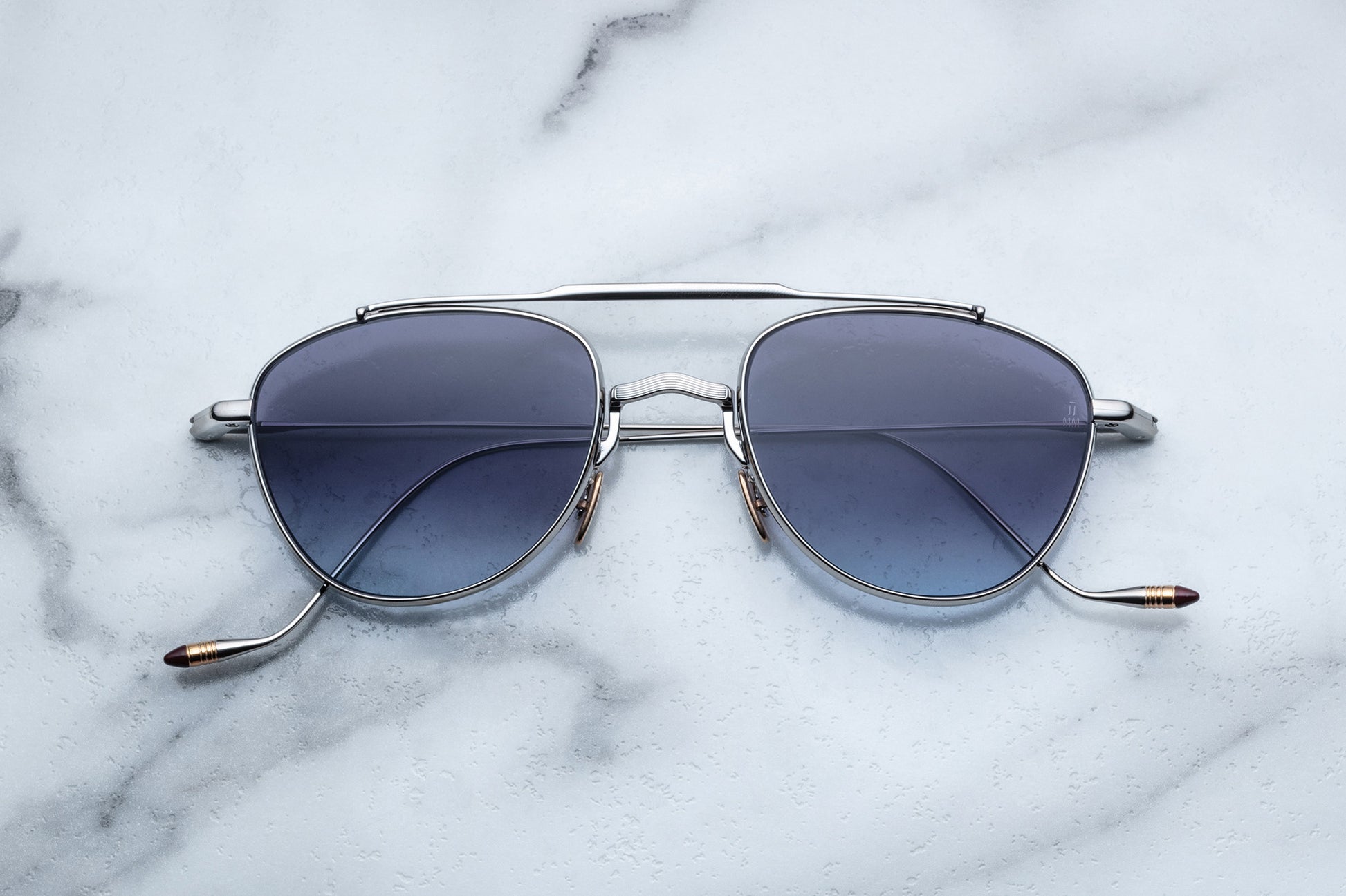 Overhead view of oval shaped sunglasses with grey gradient lenses and a silver frame