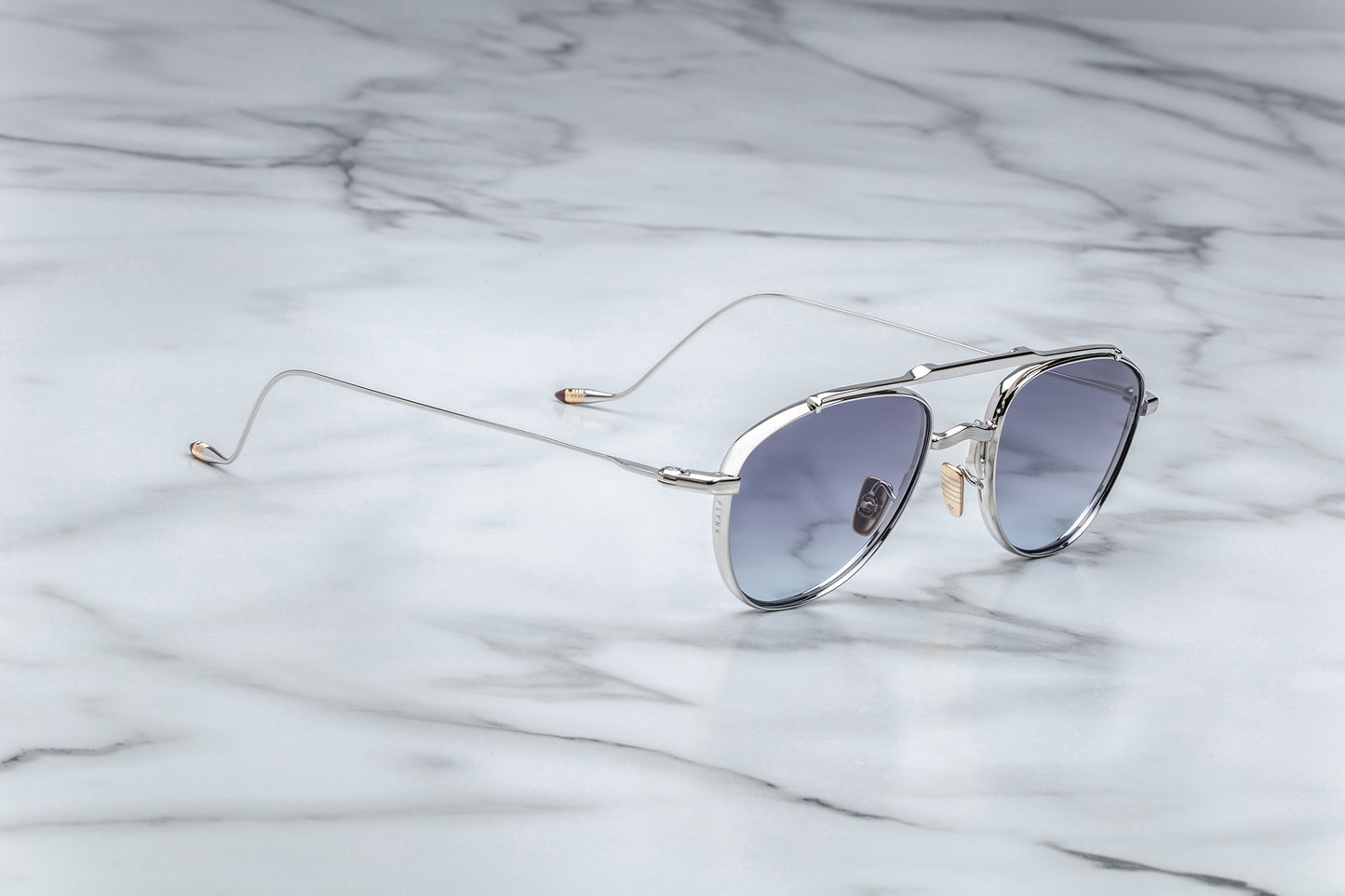 Side view of oval shaped sunglasses with grey gradient lenses and a silver frame