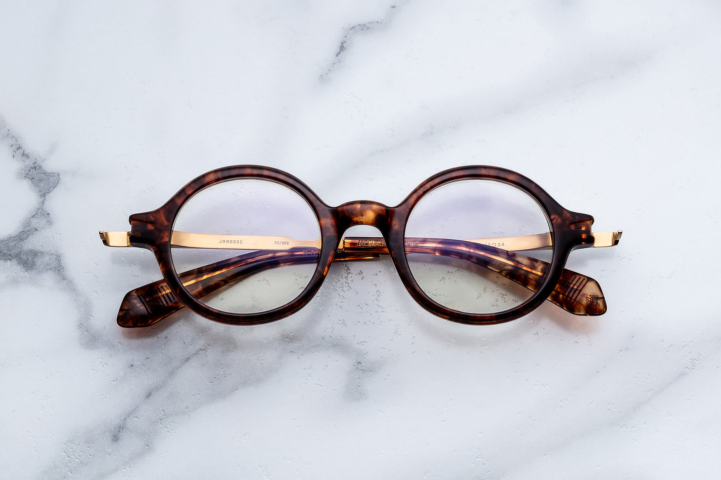 Round tortoiseshell glasses on a marble surface