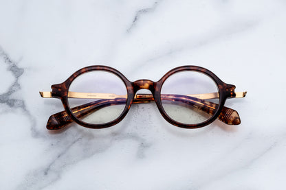 Round tortoiseshell glasses on a marble surface