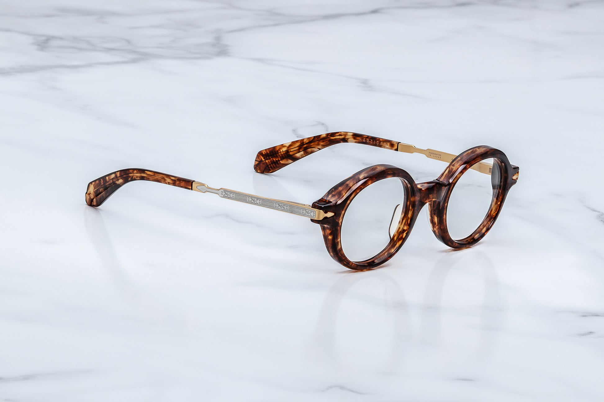 Round eyeglasses with tortoiseshell frame on a marble surface