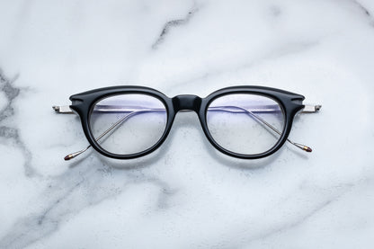 Overhead view of round black eyeglasses with gold accents
