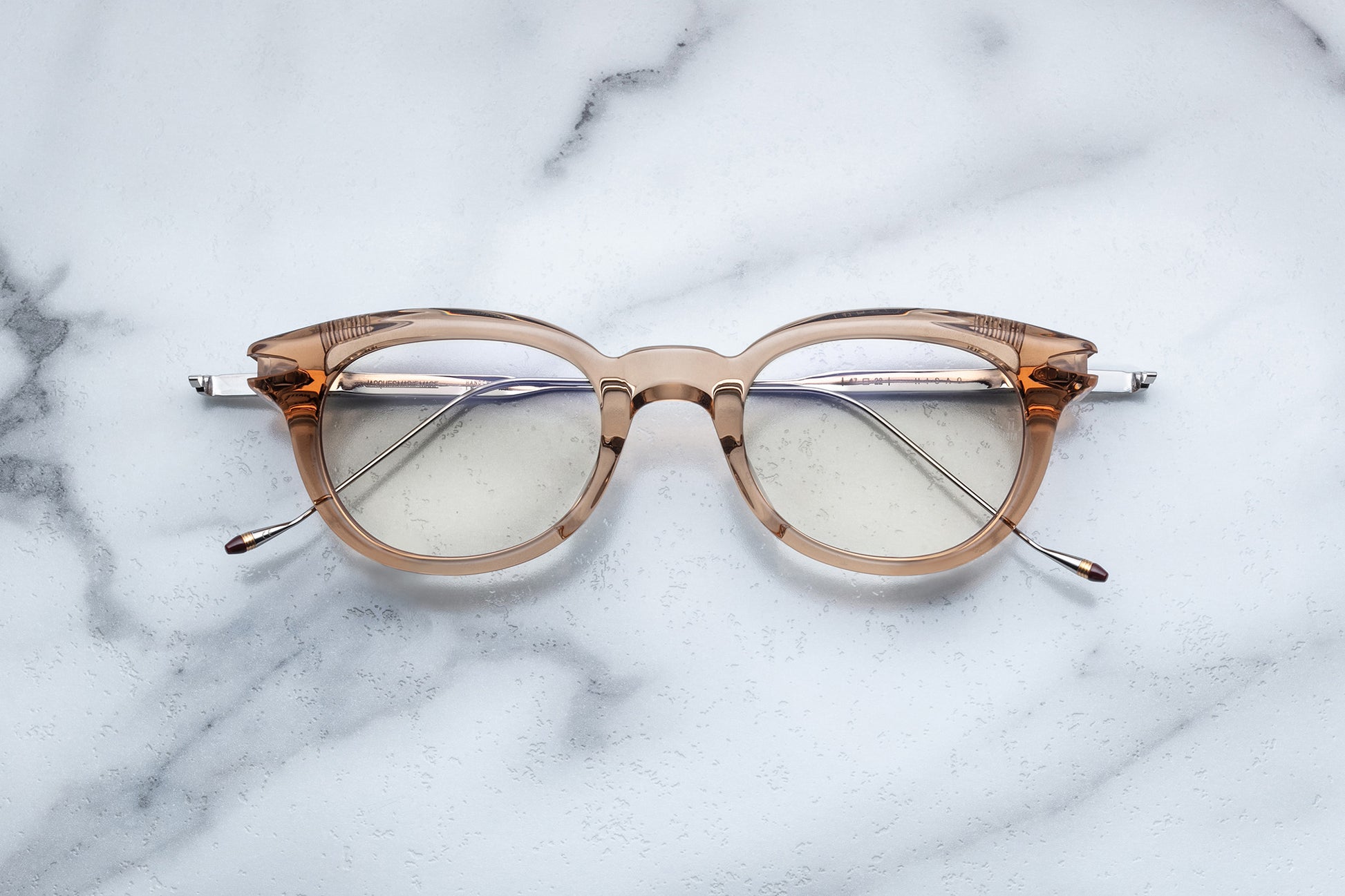 Overhead view of round translucent beige eyeglasses with silver accents