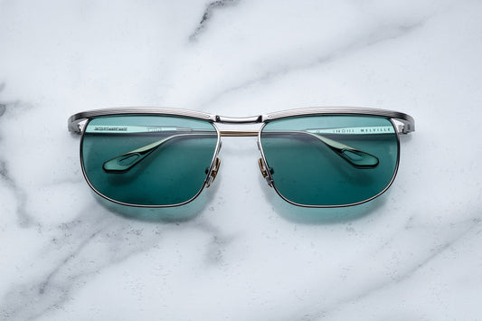 Overhead view of silver sunglasses with green lenses and gold accents