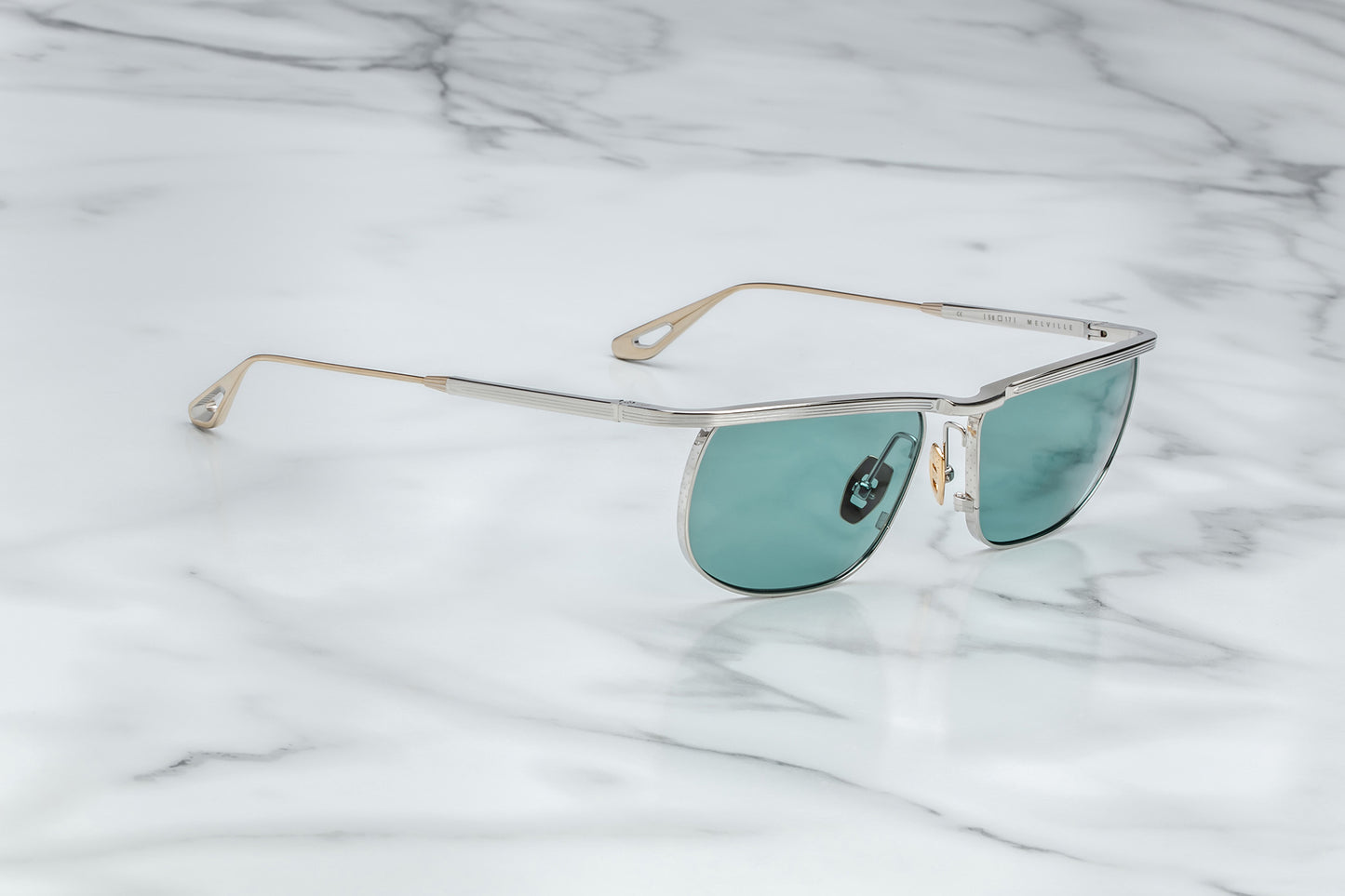 Side view of silver sunglasses with green lenses and gold accents