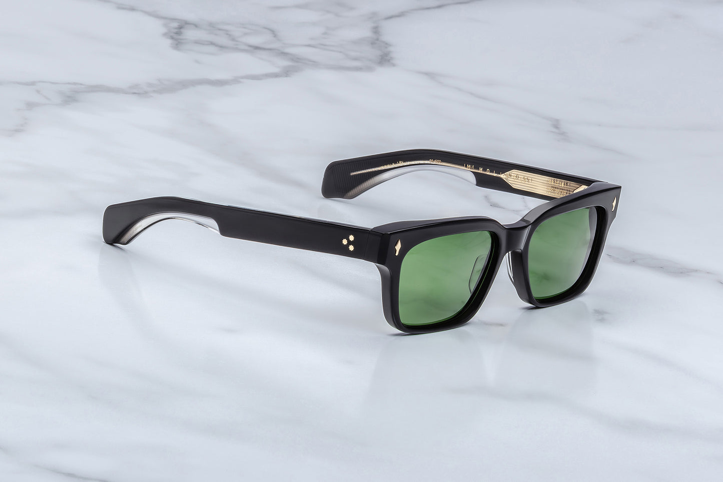 Black sunglasses with green lenses on a marble surface