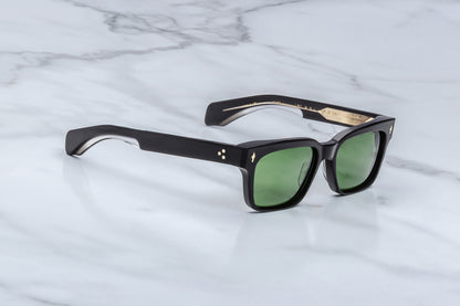 Black sunglasses with green lenses on a marble surface