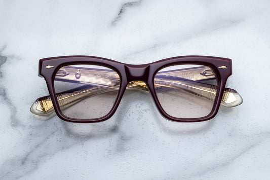 Overhead view of rectangular eyeglasses with burgundy frames and gold accents