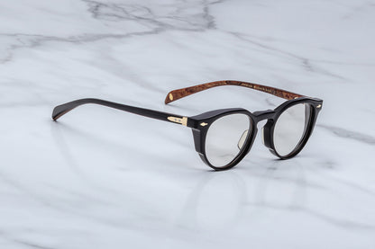 Black eyeglasses with wooden accents on a marble surface
