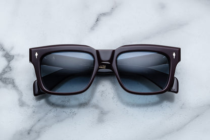 Overhead view of dark purple rectangular sunglasses with blue lenses