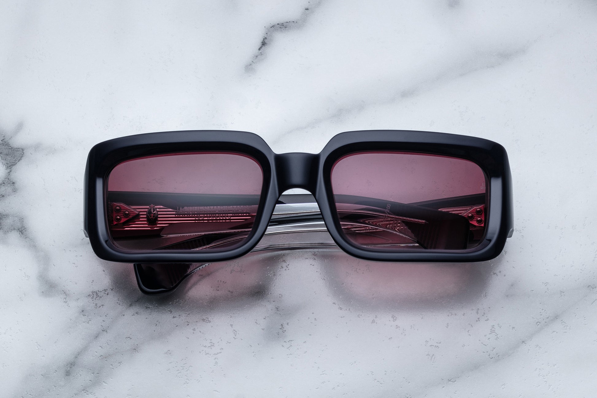 Overhead view of black rectangular sunglasses with burgundy lenses