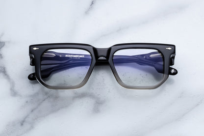 Black-framed glasses with blue-tinted lenses on a marble surface