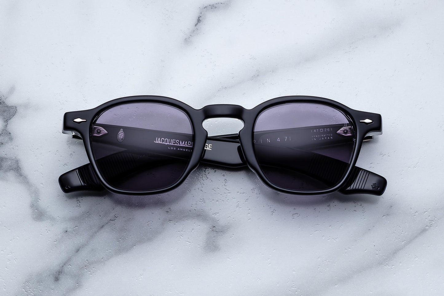 Black sunglasses with a brand logo on a marble surface