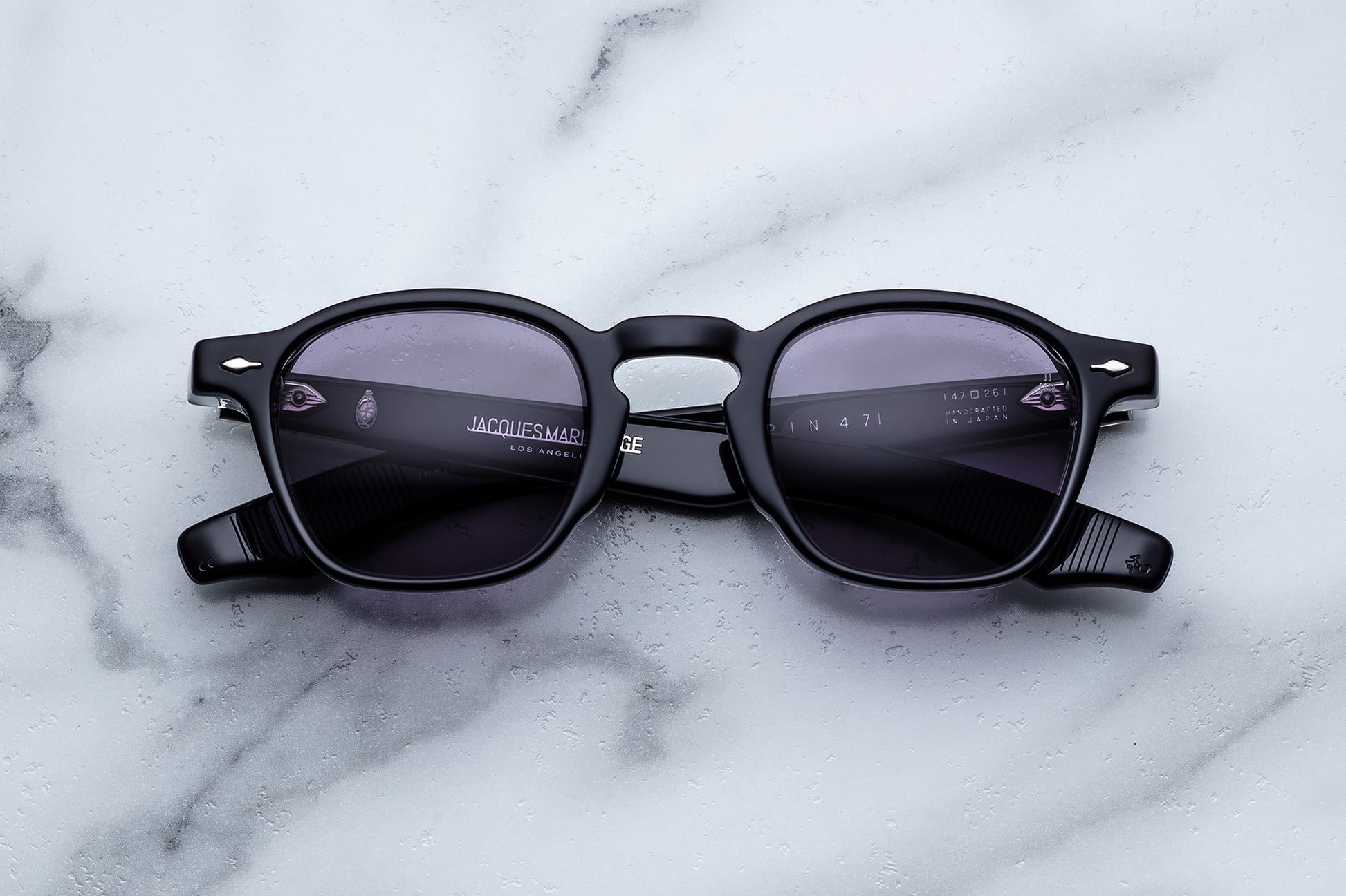 Black sunglasses with a brand logo on a marble surface