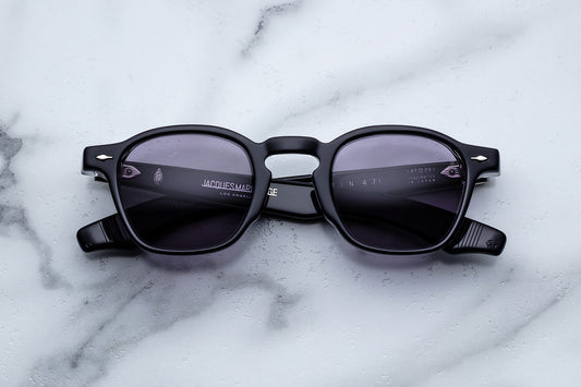 Black sunglasses with a brand logo on a marble surface