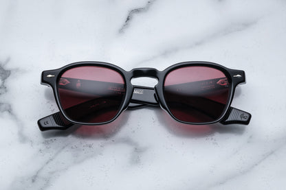 Overhead view of black rounded rectangular sunglasses with red lenses