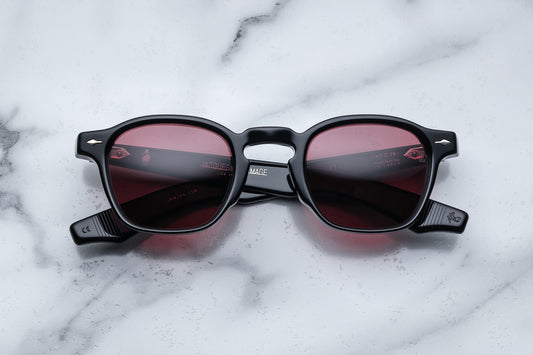 Overhead view of black rounded rectangular sunglasses with red lenses