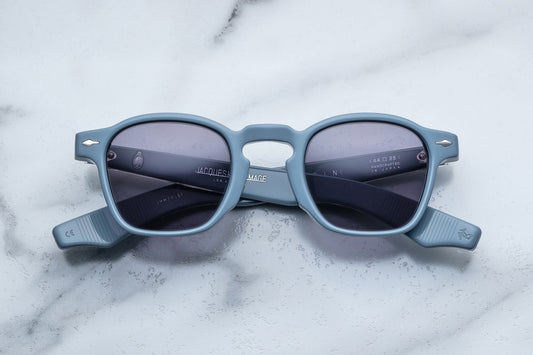 Overhead view of powder blue rounded rectangular sunglasses with purple lenses