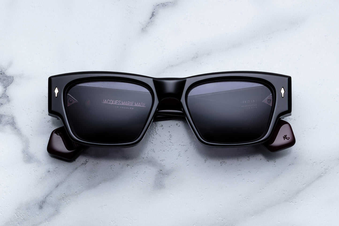 Black sunglasses with reflective lenses on a marble surface