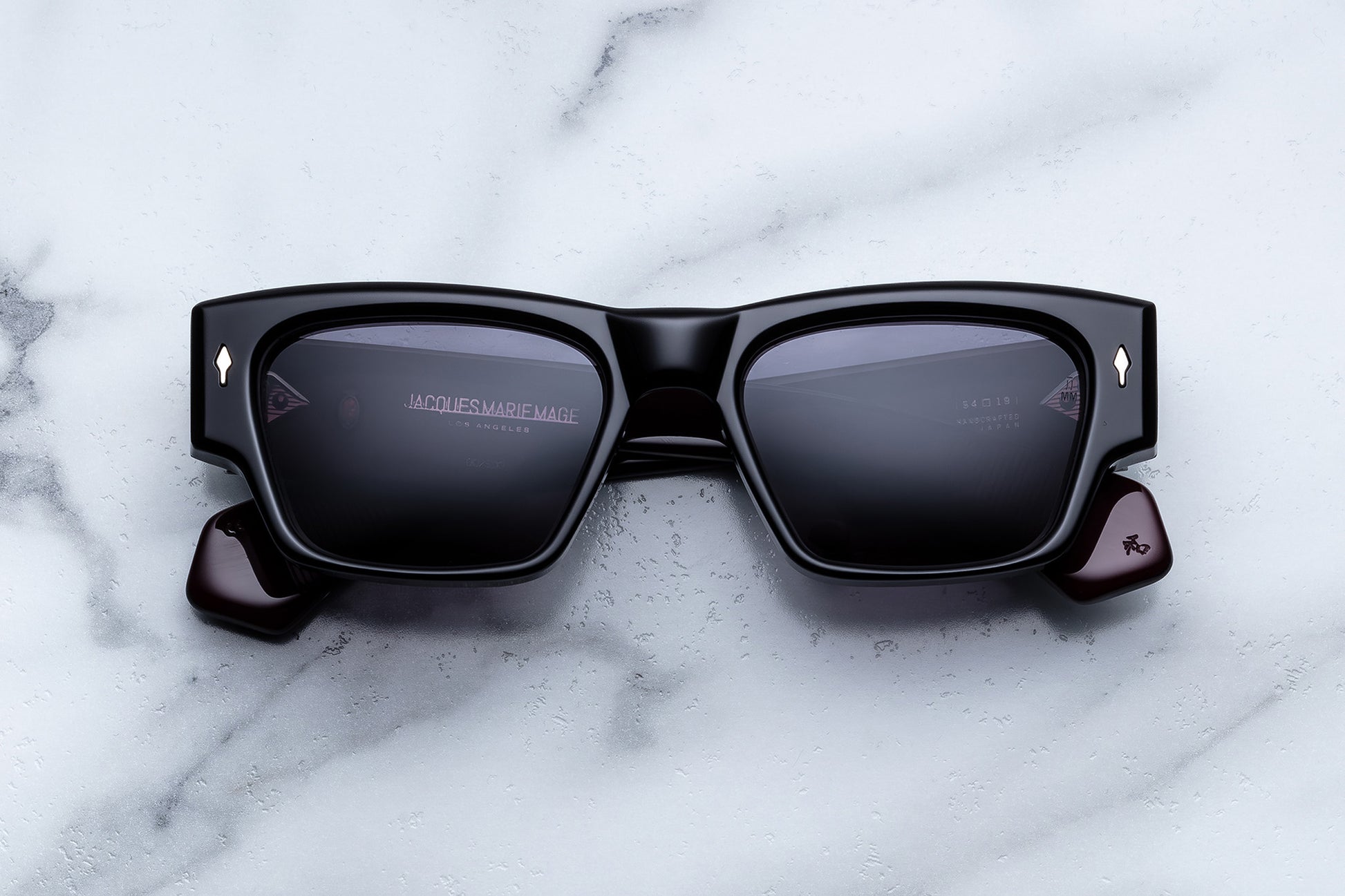 Black sunglasses with reflective lenses on a marble surface